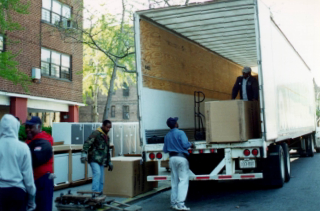 People unloading refrigerators from a truck